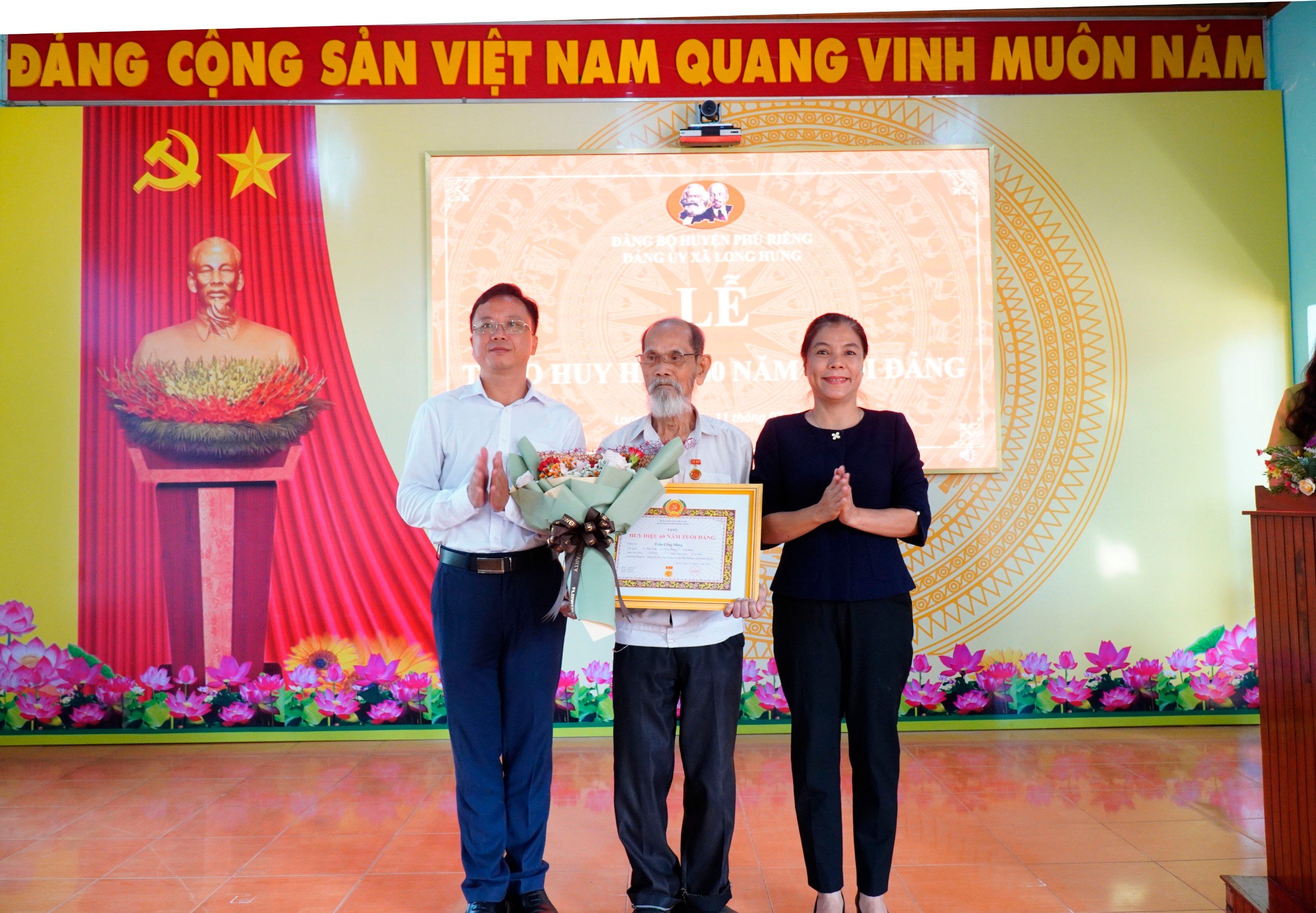 BÍ THƯ HUYỆN UỶ PHÚ RIỀNG NGUYỄN THỊ XUÂN HOÀ TRAO HUY HIỆU 60 NĂM TUỔI ĐẢNG CHO ĐẢNG VIÊN TRẦN CÔNG DŨNG